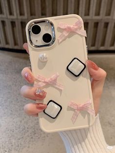 a woman holding up her phone case with bows and buttons on the back of it