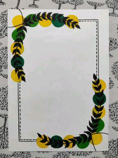 a white paper with green, yellow and black leaves in the shape of a square