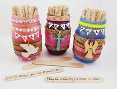 three colorful jars with wooden spoons in them and some writing on the top one