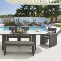 a table with chairs and a bench in front of a pool