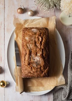 a loaf of bread sitting on top of a white plate next to a knife and fork