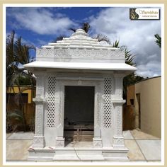 a white gazebo sitting on top of a cement ground next to a palm tree