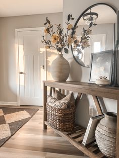 a vase with flowers sitting on top of a wooden shelf next to a mirror and other items