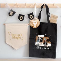 two halloween bags hanging on a wall next to a trick or treat bag and banner