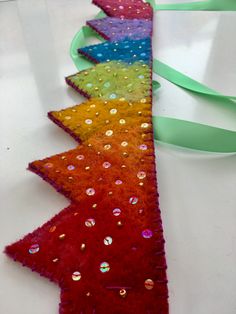 a row of christmas trees made out of felt and sequins on a table