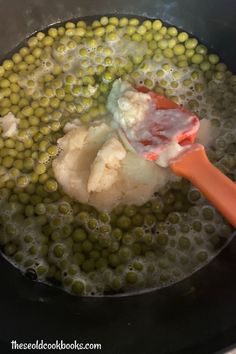 the food is being cooked in the pot with the ladle and spoon on it