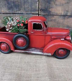 an old red truck with flowers in the back and pine cones on the front seat