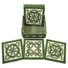 four coasters with green and white designs on them, one has a cross - stitch design