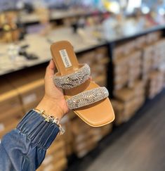 a person is holding up their shoes in front of some shelves with boxes and other items