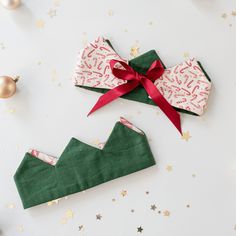 two green and red paper bags with bows on them, sitting next to christmas decorations