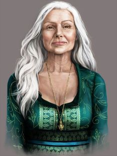 an older woman with long white hair wearing a green top and gold necklace, standing in front of a gray background