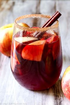 an apple sangria is served in a glass with cinnamon stick and sliced apples on the side