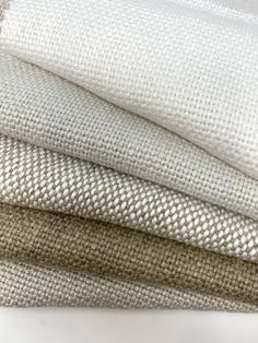 three pieces of white fabric stacked on top of each other in different sizes and colors