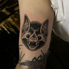 a bat tattoo on the left arm and shoulder, with an evil face in the middle