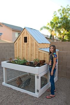 a woman standing next to a chicken coop with plants growing in the top and bottom