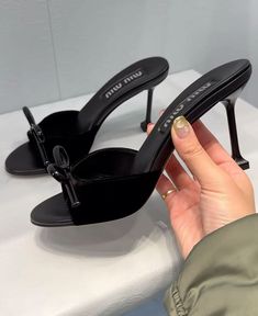 a woman's hand is holding the heel of a pair of black shoes