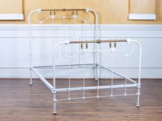 a white metal bed frame sitting on top of a hard wood floor next to a wall