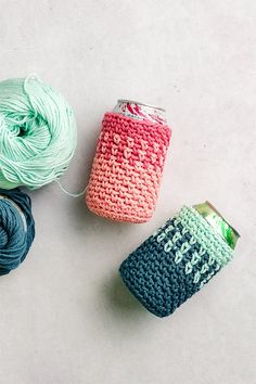 three balls of yarn next to a can of soda on a white surface with blue and pink crochet