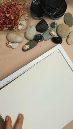 a person holding an open laptop computer next to some rocks and other items on a table