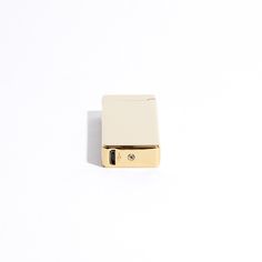 a gold lighter sitting on top of a white surface