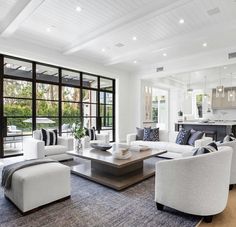 a living room filled with white furniture and lots of glass doors leading to an outdoor swimming pool