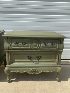 an old dresser painted green and sitting in front of a garage door