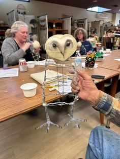 an owl sculpture being held up in front of a group of people at a table