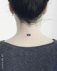 a woman with a small camera tattoo on her neck and behind her head is a black - and - white photo