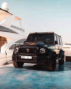 a black suv parked on top of a blue floor next to a white motor boat