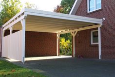 an attached carport in front of a red brick building with white trim on it