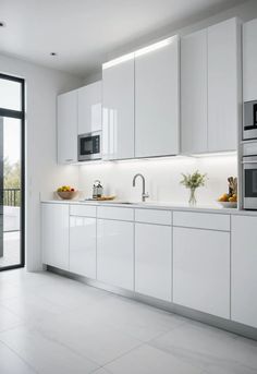 a modern kitchen with white cabinets and stainless steel appliances, along with large sliding glass doors