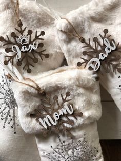 three snowflakes are hanging from the side of a white jacket that says mom and dad