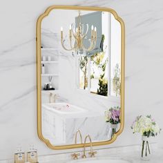 a bathroom with marble counter tops and a gold framed mirror on the wall above it