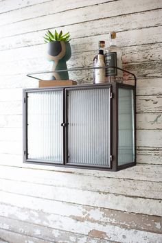 a wall mounted cabinet with bottles on it and a potted plant next to it