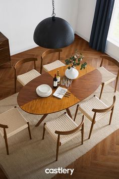 a wooden table with chairs and vases on it next to a lamp hanging from the ceiling