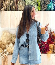 a woman standing in front of a wall holding a drink