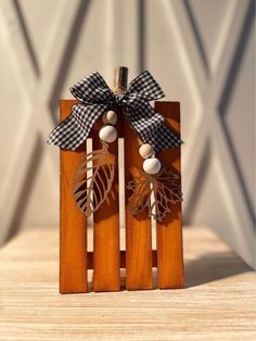 two wooden earrings with black and white leaves on them, tied together by a ribbon