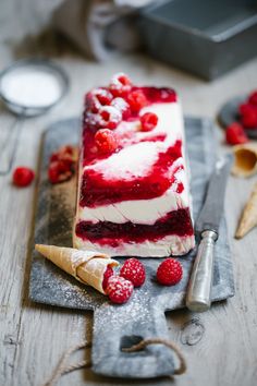 a piece of cake with raspberries and cream on it sitting on top of a wooden table