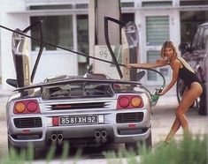 a woman in a bathing suit pumping gas into her car