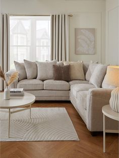 a living room filled with furniture next to a window covered in curtains and drapes