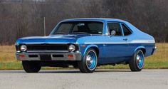 an old blue car is parked on the side of the road