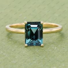 an emerald colored stone ring with two gold rings on the bottom and one blue diamond in the middle