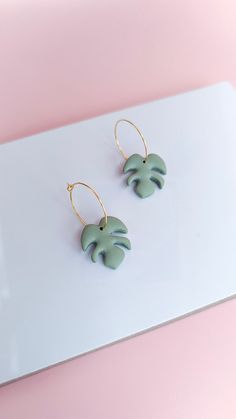 Brighten your day with these sage green monstera gold plated hoop earrings, handmade in Brighton from polymer clay. These easy-to-wear modern and minimalistic earrings are perfect for plant lovers. Please note that each earring is handmade, therefore there will be some slight variations in size and colour. Making each one unique in its own way. Made from polymer clay with gold plated hoop findings - great for sensitive ears. - Sage Green Earrings - Gold Plated - Dangle - Simple - Monstera Cheese Small Hoop Polymer Clay Earrings For Everyday, Everyday Small Hoop Earrings In Polymer Clay, Trendy Green Leaf-shaped Jewelry, Green Small Hoop Earrings For Everyday, Handmade Everyday Leaf-shaped Jewelry, Minimalist Green Hoop Earrings With Ear Wire, Minimalist Green Polymer Clay Earrings, Handmade Green 14k Gold Filled Earrings, Handmade Minimalist Green Jewelry