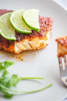 a white plate topped with fish covered in sauce and lime slices