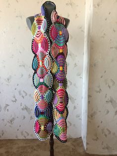 a mannequin made out of multicolored pieces of fabric on a wooden stand