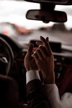 a person in a car holding their hand up to the dashboard light, while wearing a suit and tie