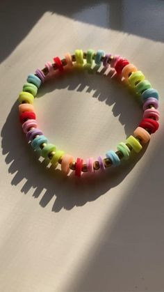 a bracelet made out of colorful beads on top of a white surface with the word love spelled in small letters