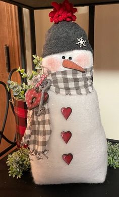 a snowman with a hat and scarf on it's head sitting next to a potted plant