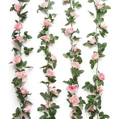 pink roses are arranged on the side of a white wall with green leaves and stems