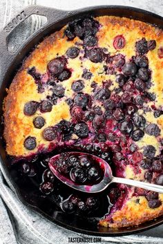 a blueberry cobbler in a cast iron skillet with a spoon